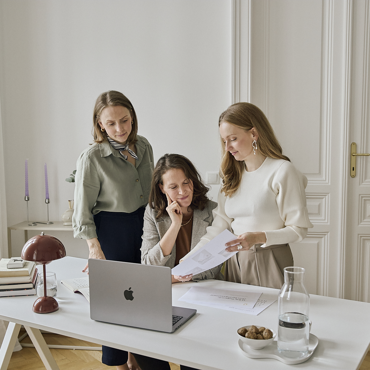 Three women from Glasswing Collective collaborating at a laptop, working on brand strategy and design.